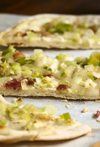 Flammkuchen serviert auf einem Pizzablech.